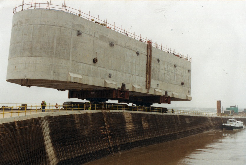 A construction view of the A6 Manchester Airport Relief Road project, showcasing a large retaining wall built using Geoquest Co. Ltd.'s precast concrete facing panels. The image highlights the integration of the road with surrounding infrastructure, illustrating the scale of the project and the innovative design solutions employed for the retaining walls and bridge abutments.