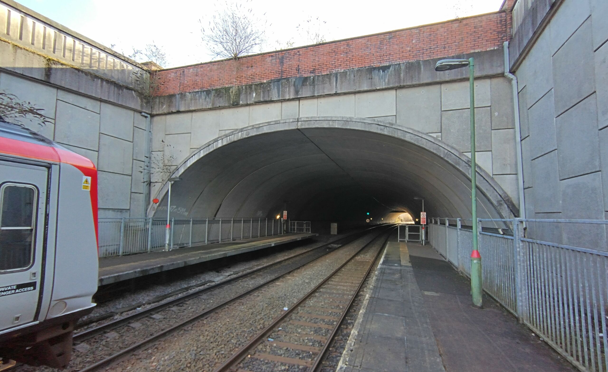 A construction view of the A6 Manchester Airport Relief Road project, showcasing a large retaining wall built using Geoquest Co. Ltd.'s precast concrete facing panels. The image highlights the integration of the road with surrounding infrastructure, illustrating the scale of the project and the innovative design solutions employed for the retaining walls and bridge abutments.