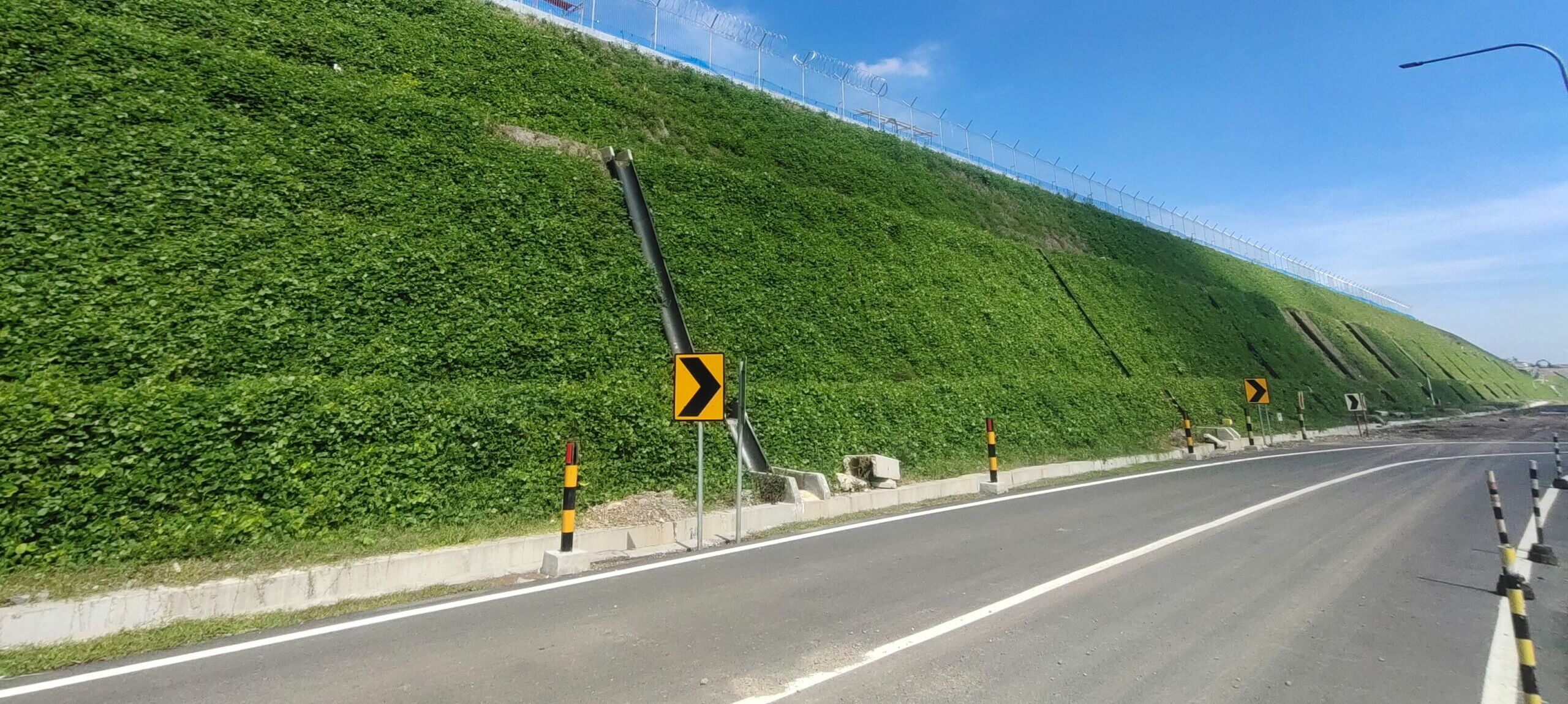 Vegetated Reinforced Steep Slope for Airport Infrastructure Reinforced steep slope with green vegetated facing supporting airport infrastructure, designed using Geoquest UK Geosynthetic reinforcement solutions