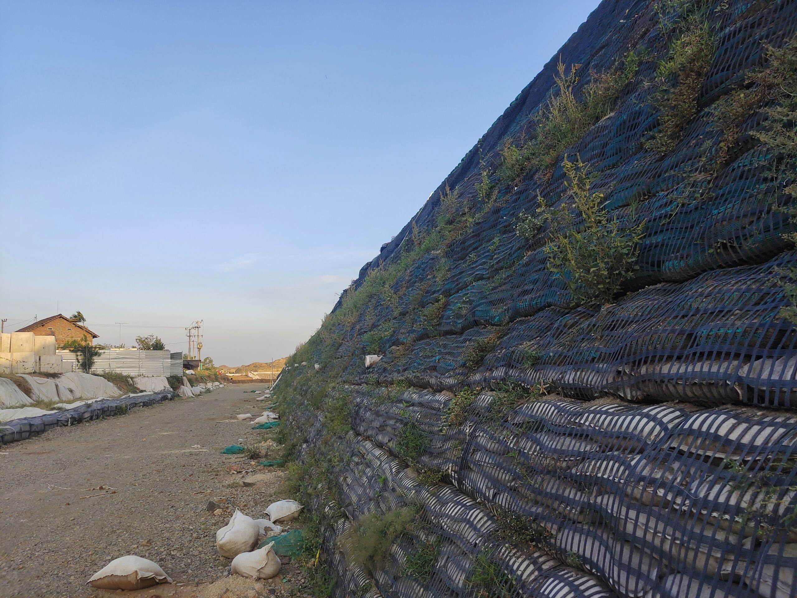 Reinforced Green Slope with Geosynthetic Wrap for Sustainable Infrastructure Steep reinforced slope using geosynthetic wrap and establishing vegetation, designed for sustainable ground stabilisation in transport and infrastructure projects.