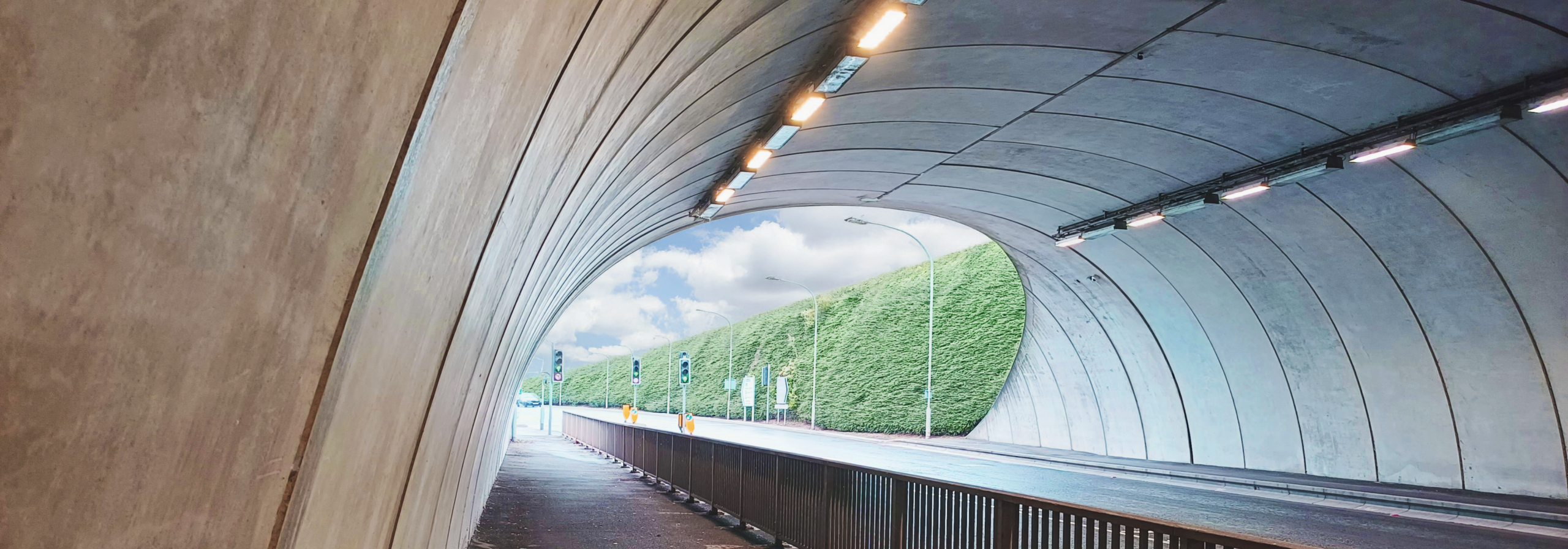 Internal View of Geoquest Cut‑and‑Cover Tunnel with Pedestrian Walkway at Heathrow Airport Interior view of a cut‑and‑cover tunnel at Terminal 5, Heathrow Airport, showing the roadway, pedestrian walkway and curved concrete structure.